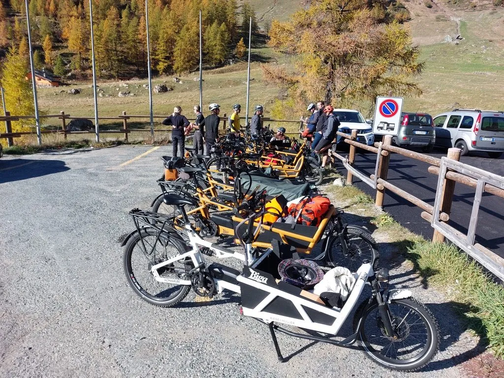 BigaAdventure 2025, Cervinia — cargo bike in fila lungo la strada tra i larici